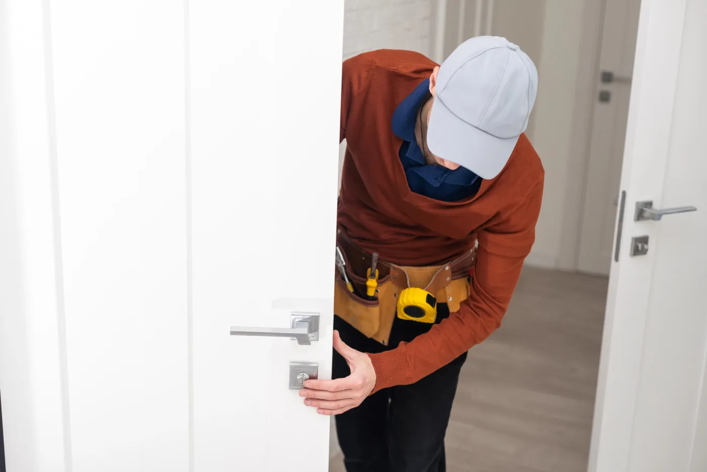 Artisan du collectif posant une serrure encastrée sur une porte d'entrée dans l'Essonne